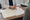 A person in a white coat points to paperwork across a desk.