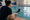 Swim instructor takes notes on a clipboard while observing a swimmer practicing in an indoor pool.