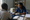 Healthcare worker in gloves examines a patient’s hand at a clinic desk with medical supplies and records nearby.