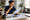 Woman reviews home floor plans and property documents at a dining table in a bright living space.