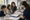 A healthcare worker reviews paperwork with a mother and two children at a table.
