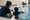 Swim instructor guides a child holding a kickboard in an indoor pool.