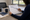 Person points to dates on a large calendar while seated at a desk near windows.